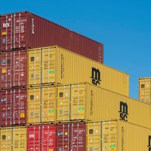 Colorful shipping containers stacked high under a clear blue sky, displaying industrial logistics.